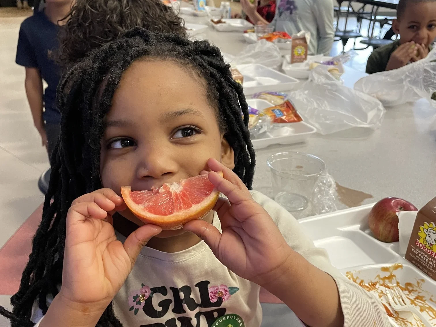 Student girl holding slice of grapefruit